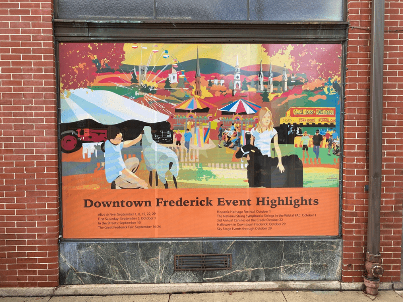 Mural on a window with children in the foreground petting animals and a ferris wheel in the background